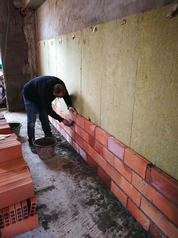 Un uomo sta posando dei mattoni su un muro.