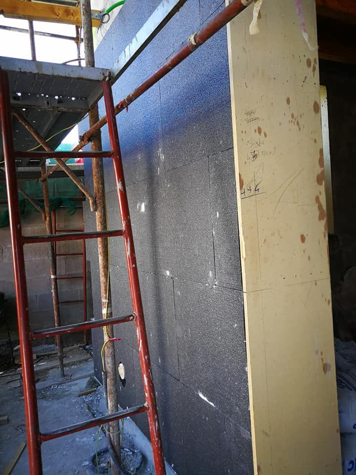 Una scala è posizionata in cima a un'impalcatura accanto a un muro.
