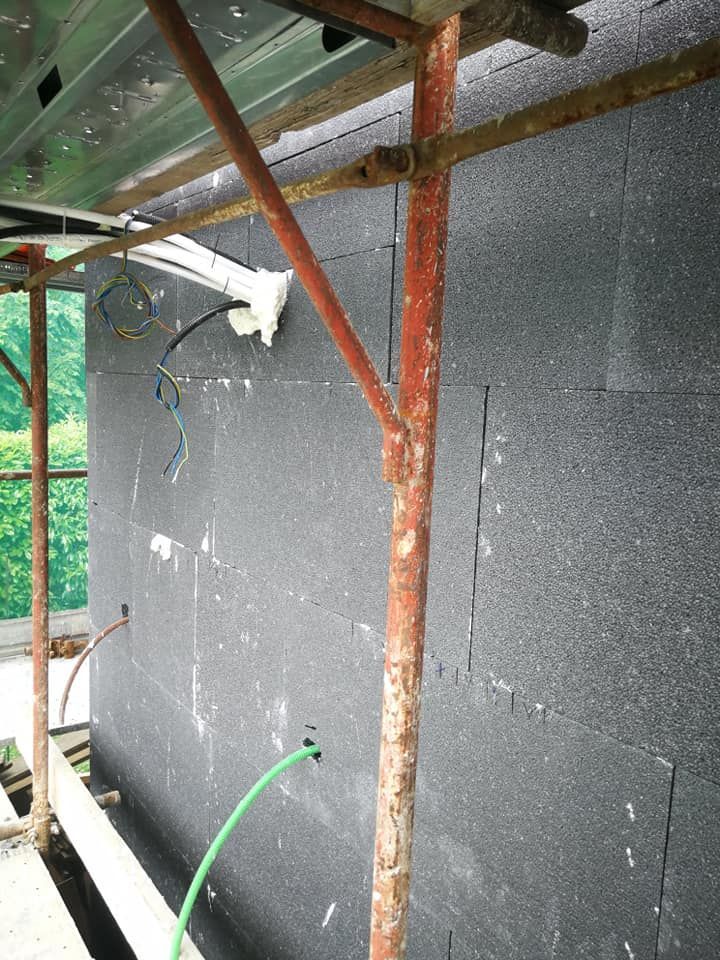 Un tubo verde è attaccato a un'impalcatura accanto a un muro