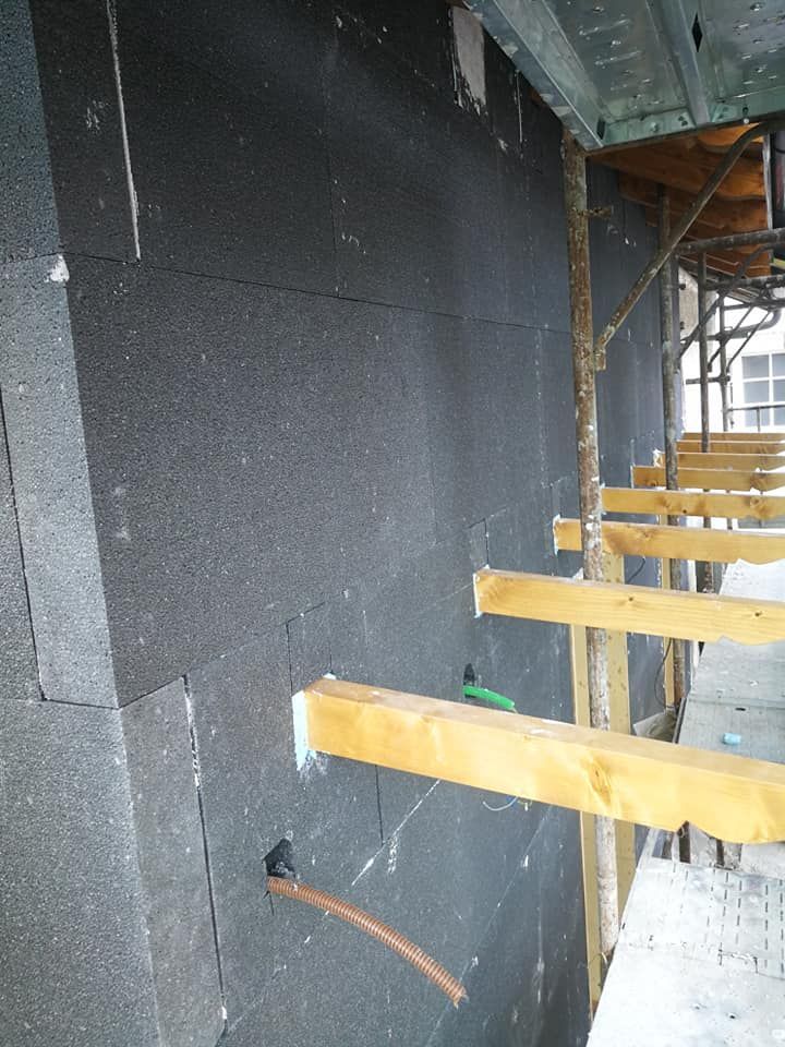 Un cantiere con impalcature e un muro nero