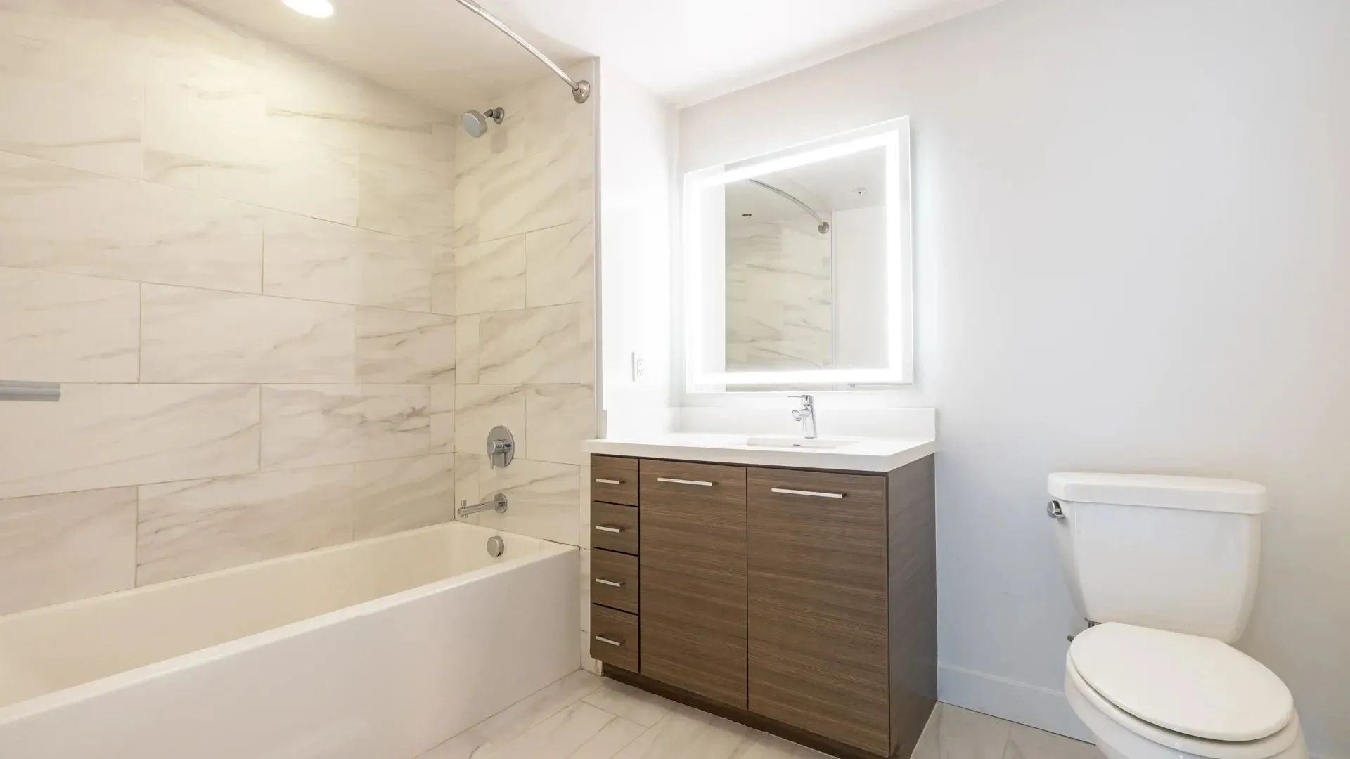 Bathroom with a modern vanity, illuminated mirror, and a bathtub at Next on Sixth Los Angeles