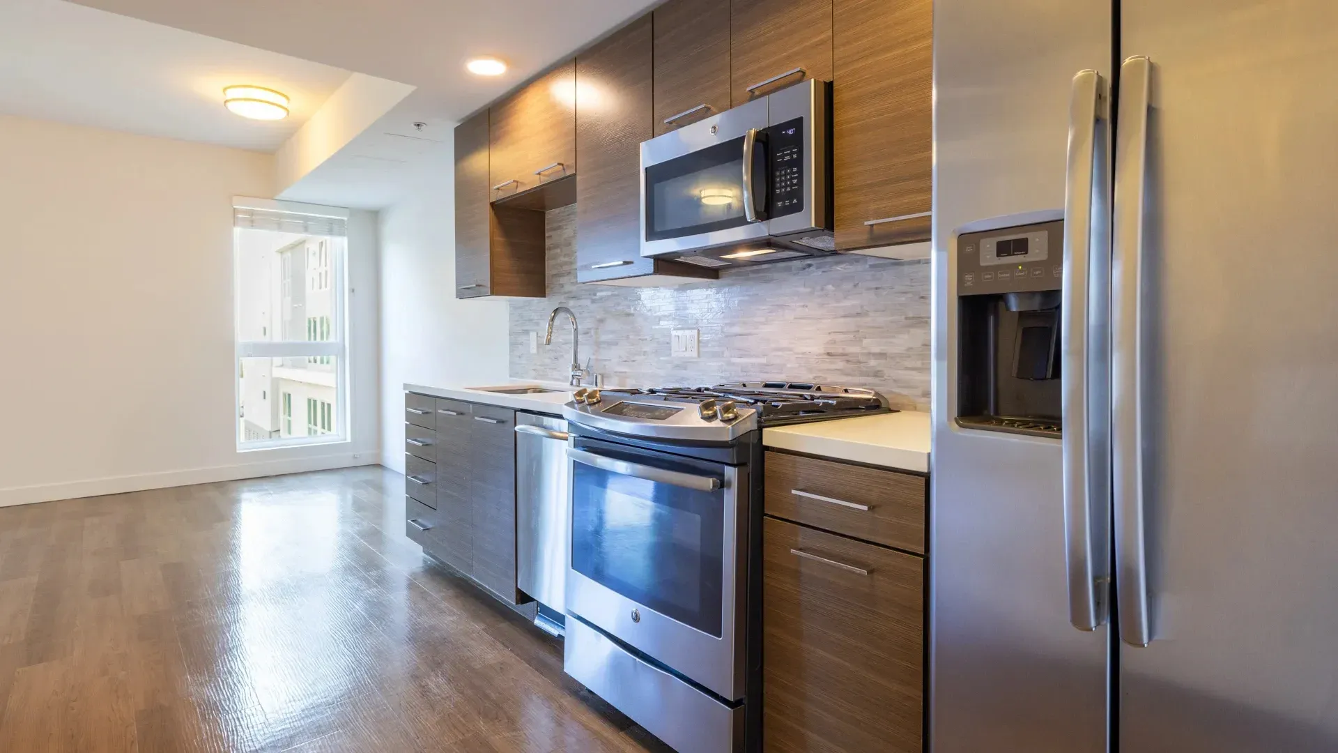 Modern kitchen with stainless steel appliances and wood cabinetry at Next on Sixth Los Angeles