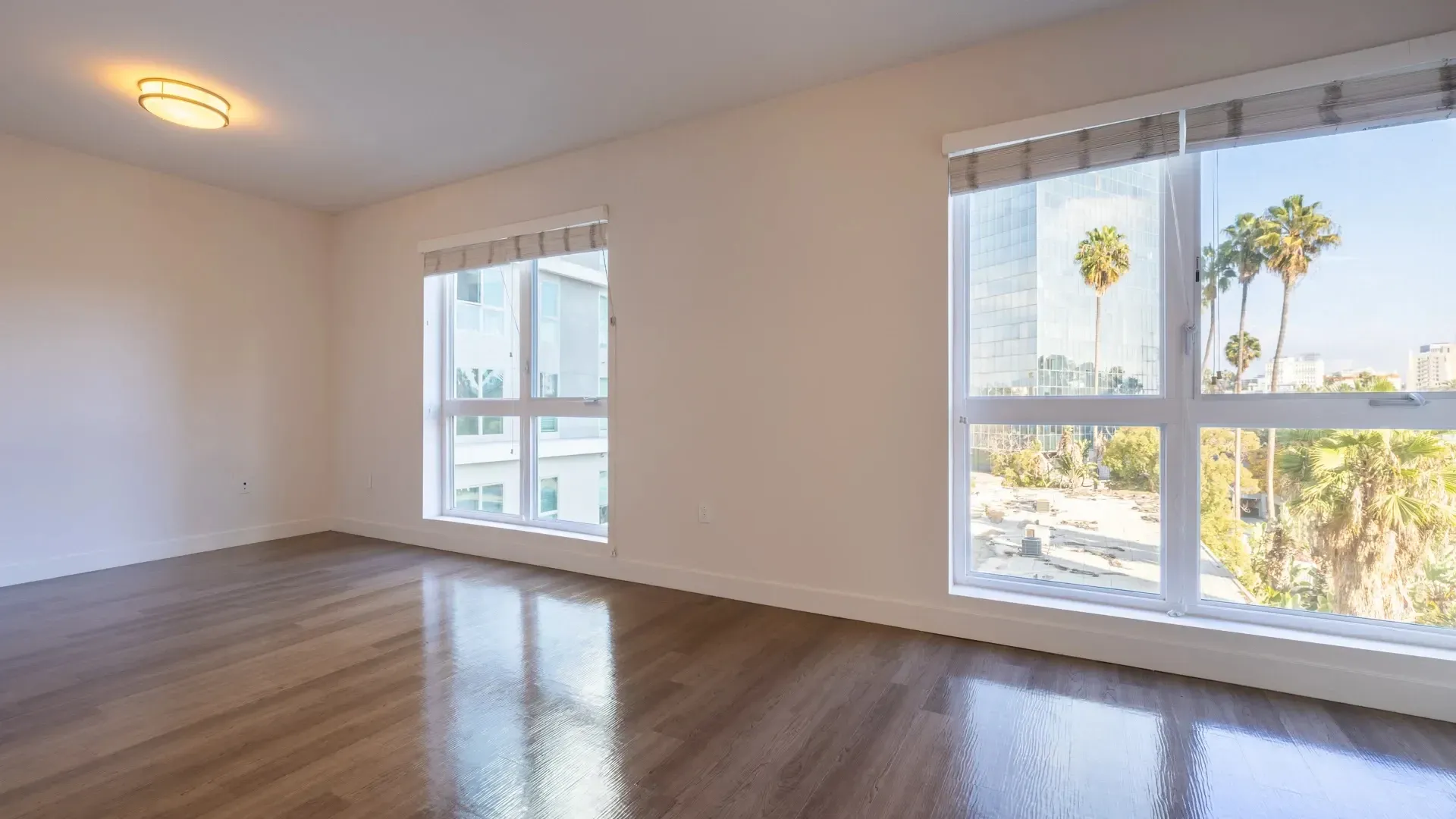Empty apartment living room with large windows and city view at Next on Sixth Los Angeles