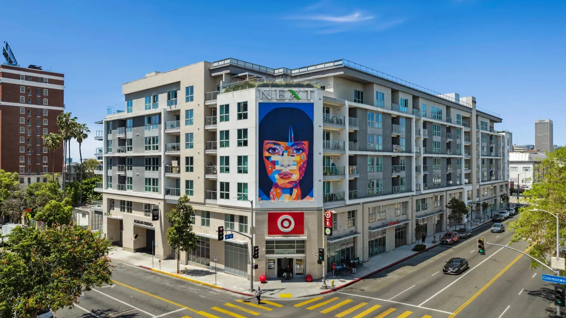 The exterior of the NEXT apartment building with a large mural of a woman's face at Next on Sixth Los Angeles