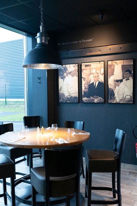 Intérieur d'un bar avec des clients, des bouteilles de champagne et une grande suspension lumineuse.