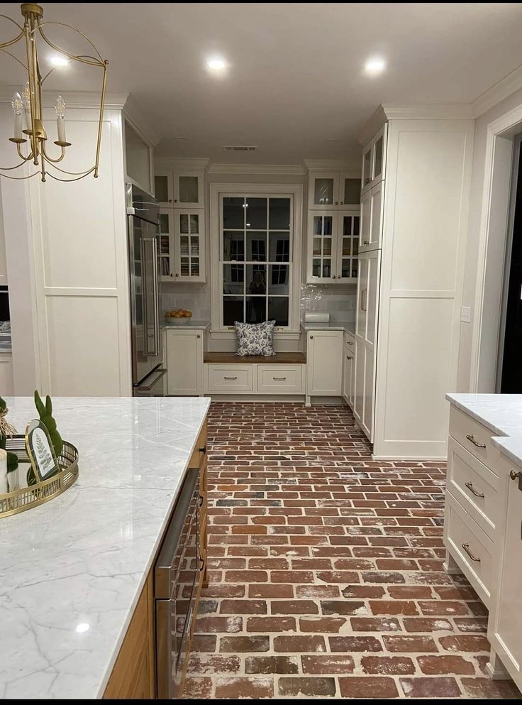 A kitchen with a brick floor and white cabinets