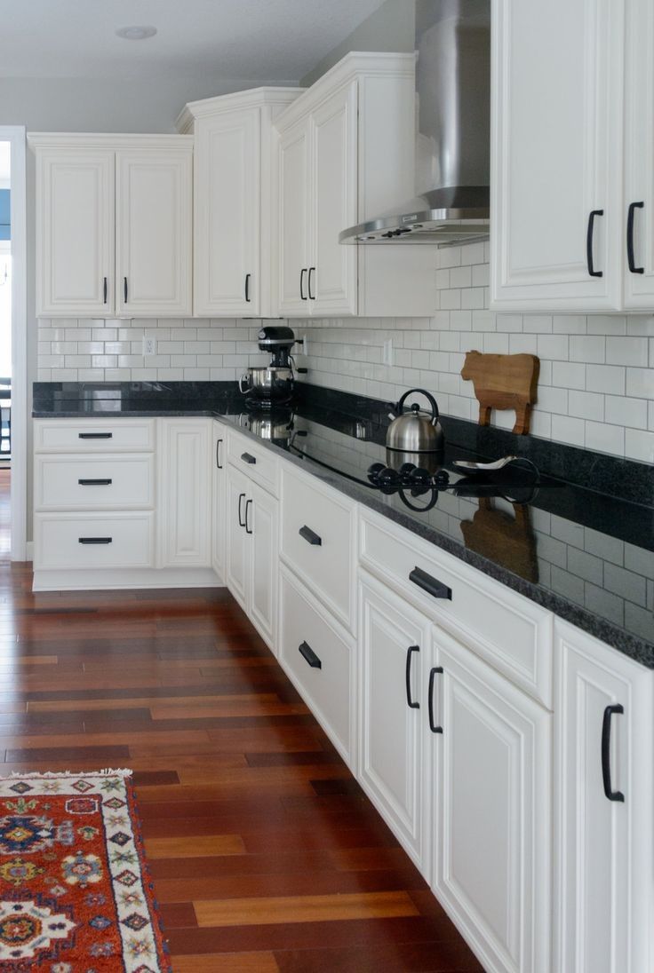 A kitchen with white cabinets and black counter tops