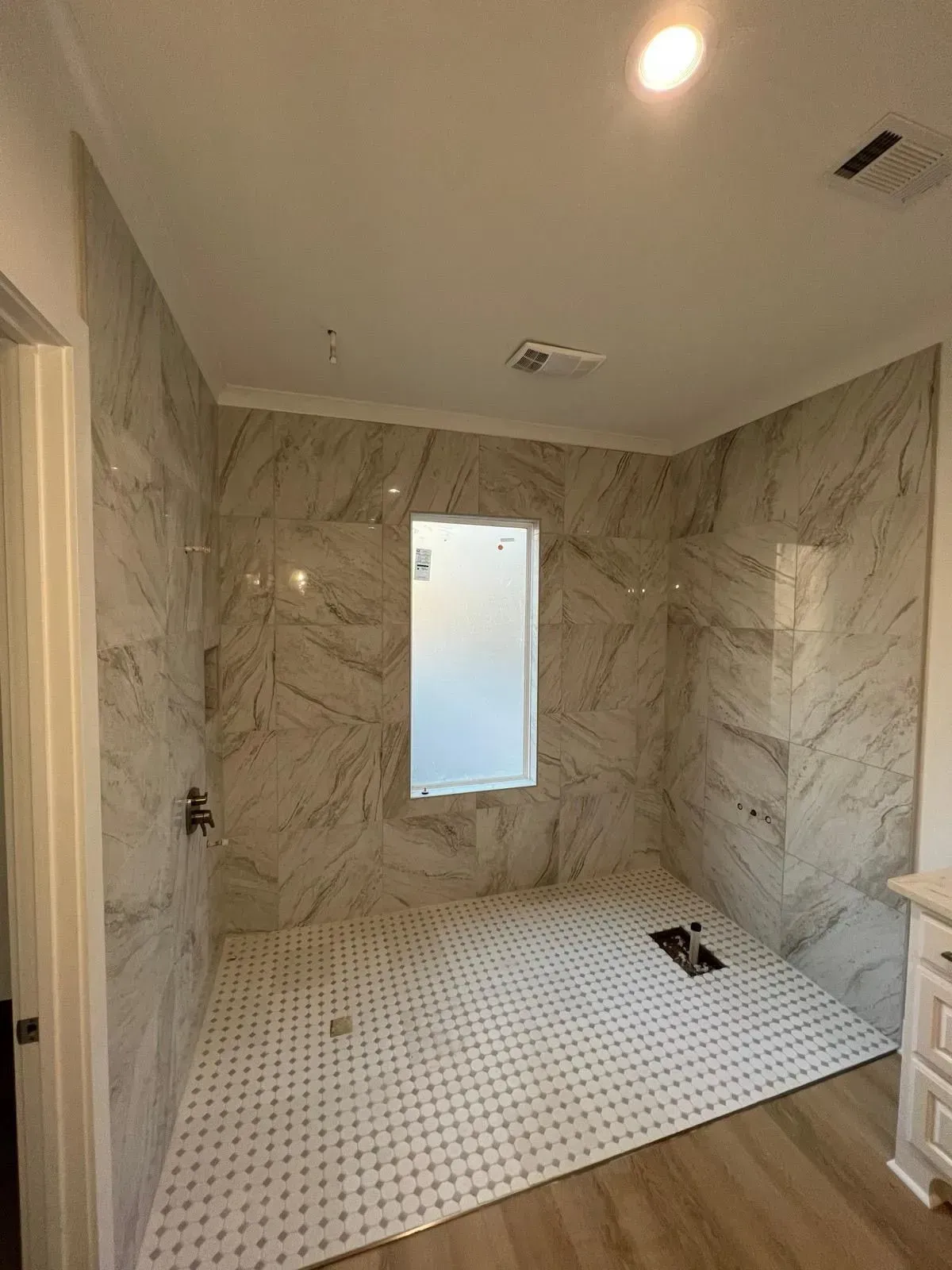 A bathroom with marble tiles and a walk in shower.