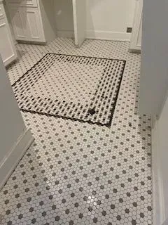 A bathroom with a black and white tile floor.