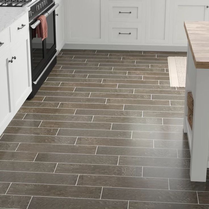 A kitchen with a brown tile floor and white cabinets