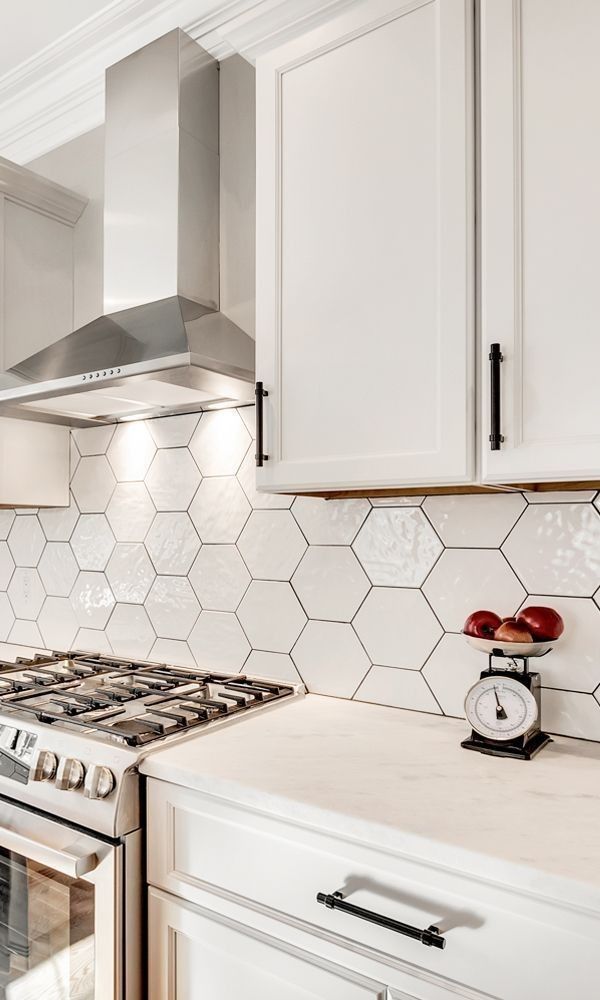 A kitchen with white cabinets , a stove , and a scale on the counter.