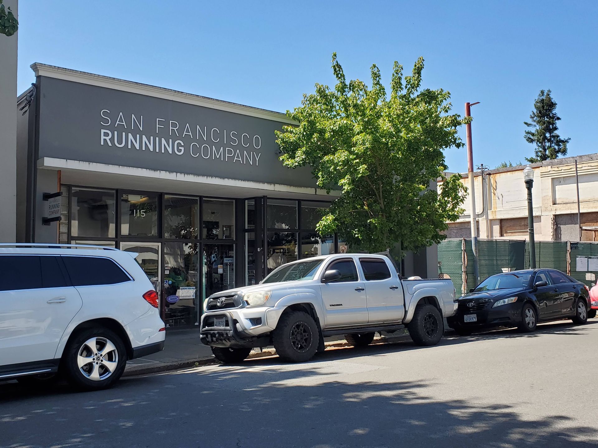 A white truck is parked in front of a building that says san francisco running company.