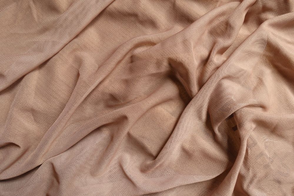Beige fabric with textured snakeskin-like pattern, draped in soft folds.