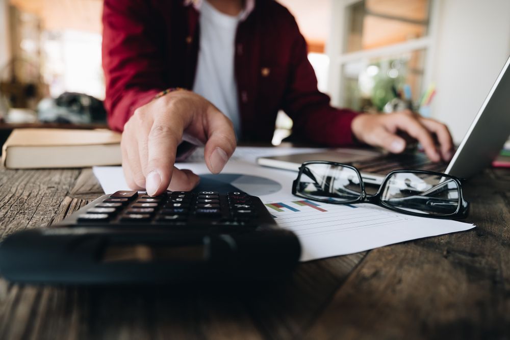 A Man is Using a Calculator — Townsville Accounting In Hyde Park, QLD