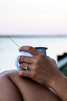 A woman is holding a cup of coffee with a straw in her hand.