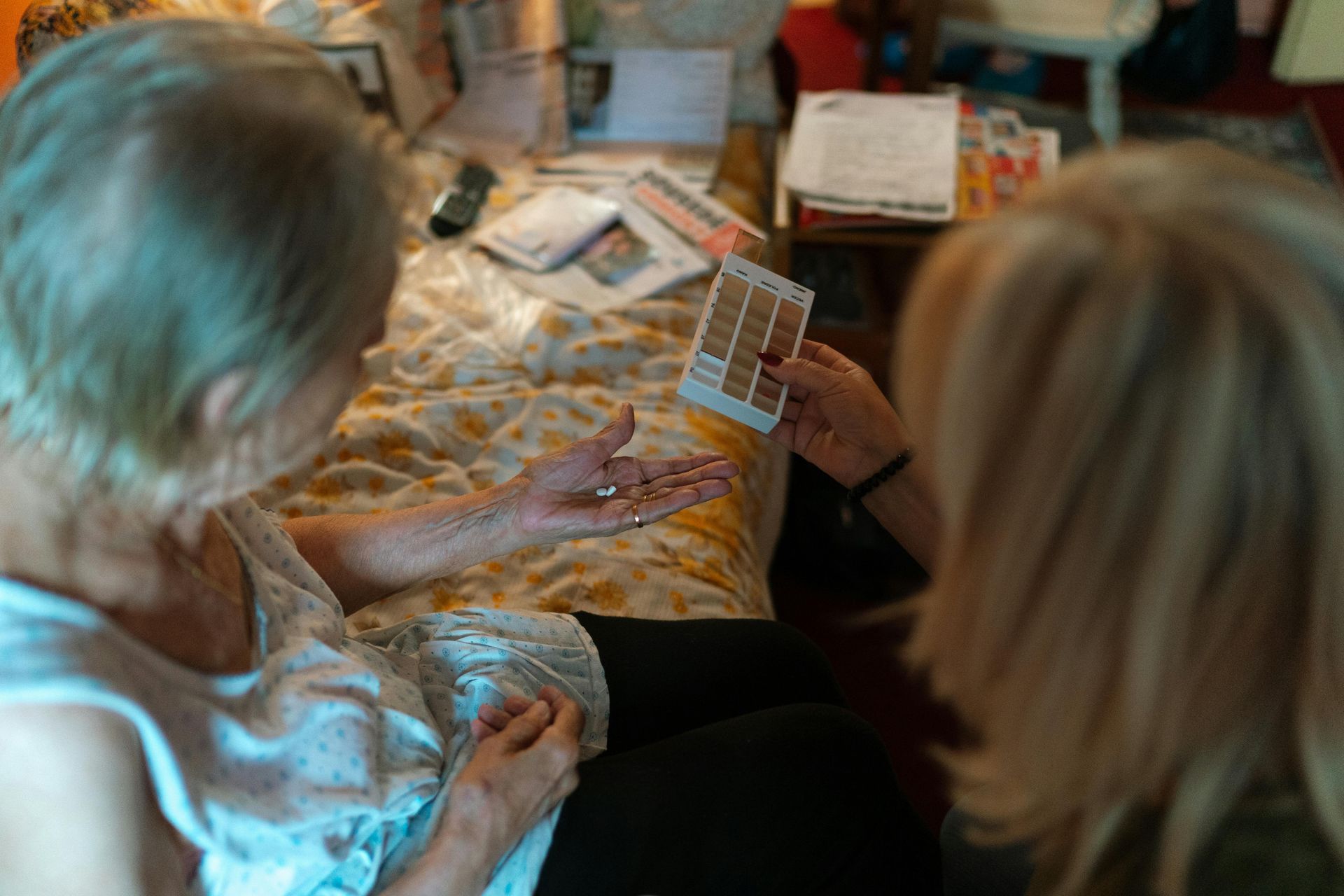 A woman is holding a box of pills in her hand while another woman looks on.