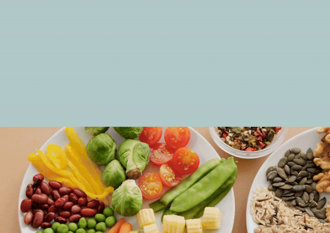 A white plate filled with colorful raw vegetables like peppers, beans, peas, Brussels sprouts, and tomatoes.