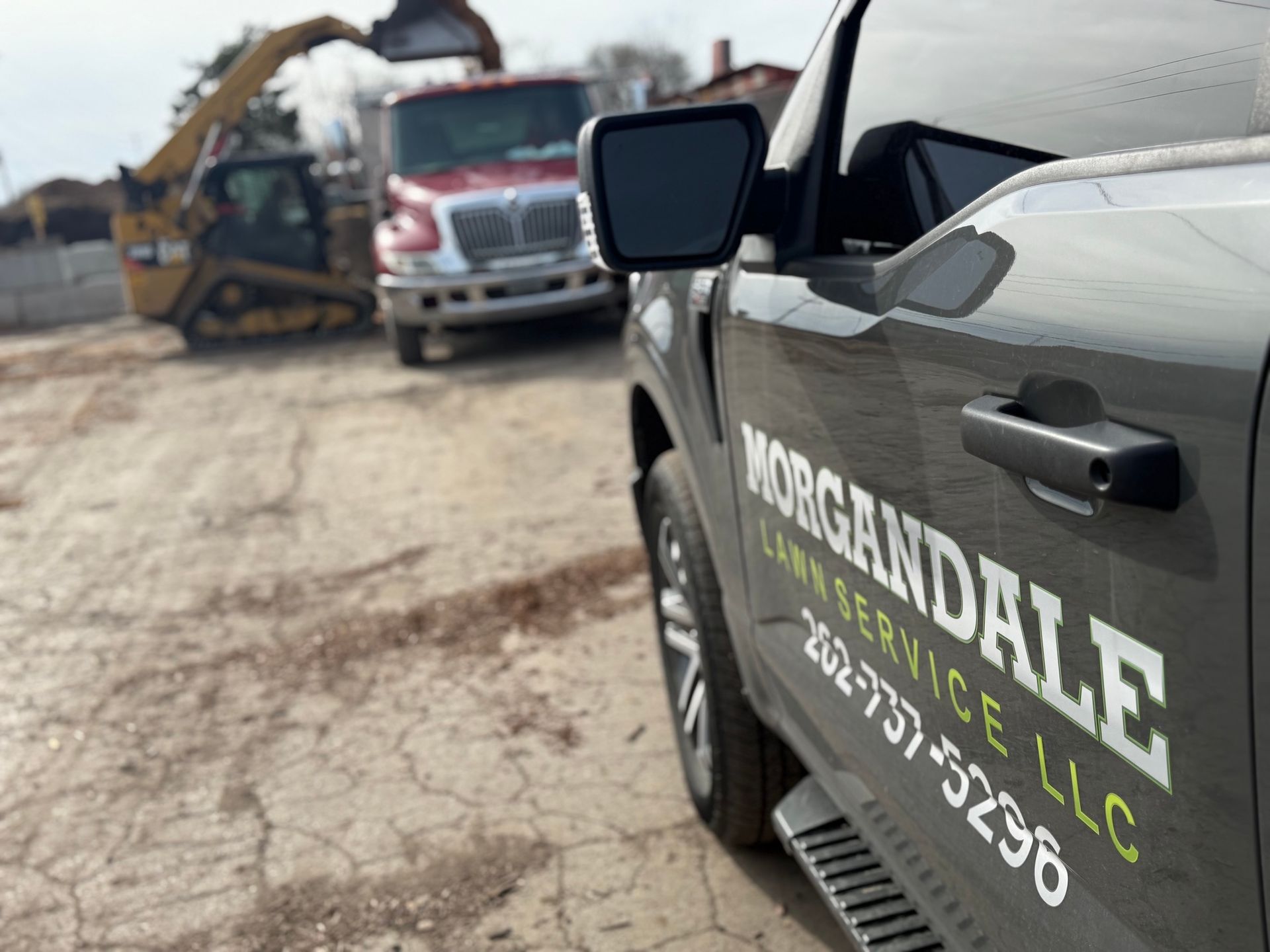 Utility truck with “Morgandale Contracting LLC” lettering parked at a construction site with heavy equipment nearby
