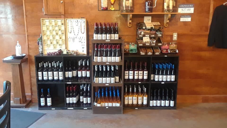 Shelves filled with various wine bottles for sale, arranged in a wooden display against a wood-paneled wall.