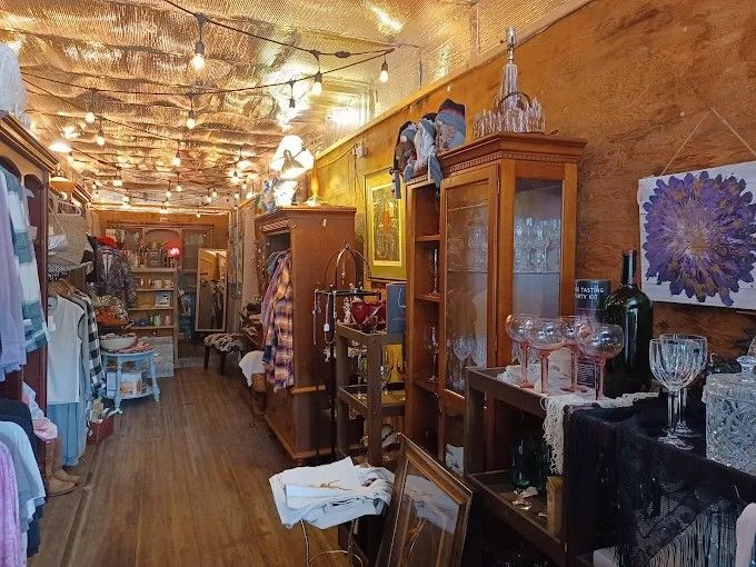 Clothing racks filled with shirts and pants in a rustic-style store with warm string lights hanging from the ceiling.