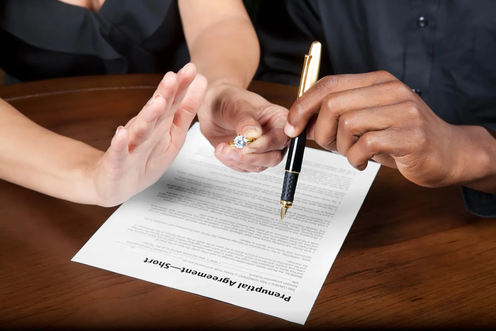Person refusing to sign a document while holding a ring over it.