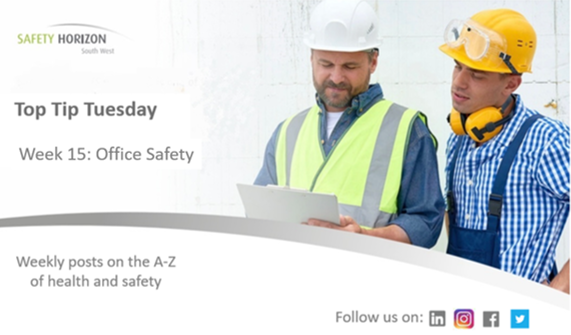 Two men wearing hard hats and safety vests are looking at a piece of paper.