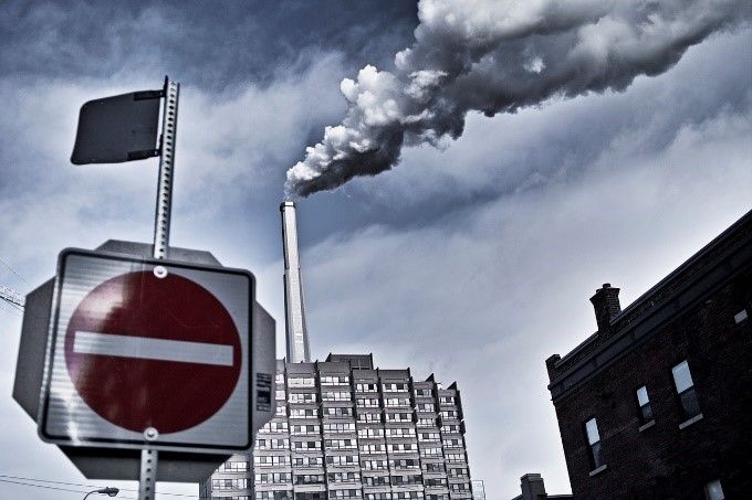 Smoke is coming out of a chimney next to a no entry sign