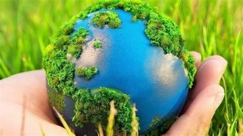 A person is holding a blue globe covered in green moss.