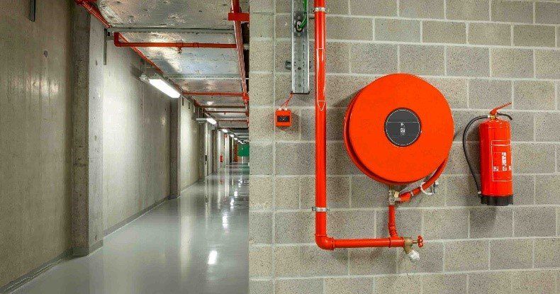 A fire extinguisher is hanging on a brick wall next to a fire hose.