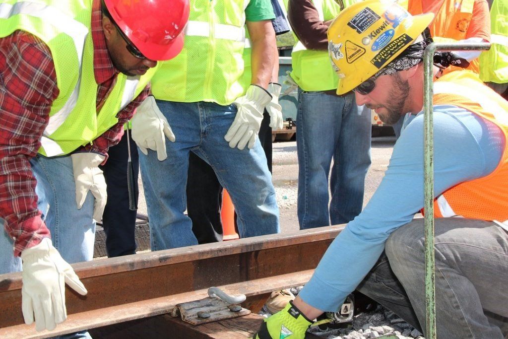 A group of construction workers are working on a railroad track
