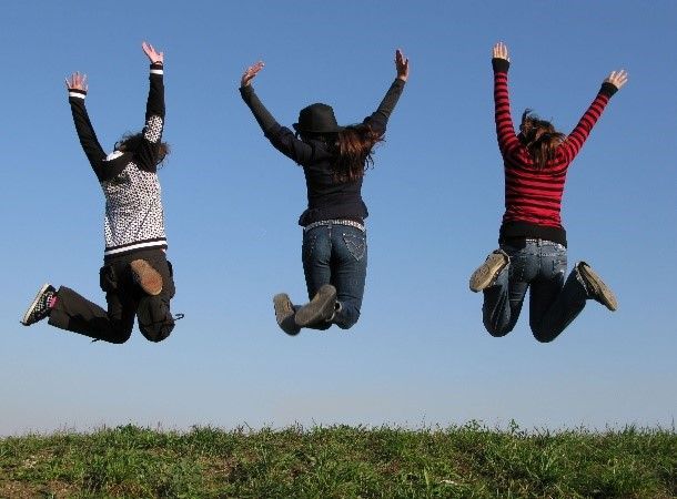 Three people are jumping in the air with their arms in the air