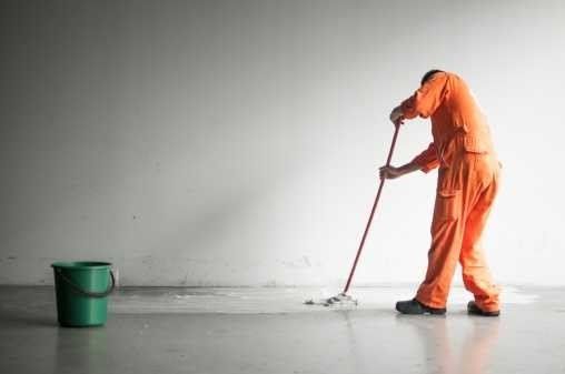 A man is cleaning the floor with a mop and bucket.