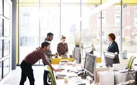A group of people are standing around a table in an office.