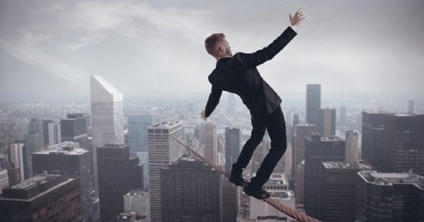 A man in a suit is walking on a tightrope over a city.