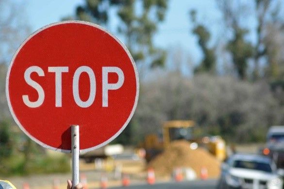 A person is holding a stop sign in front of a construction site