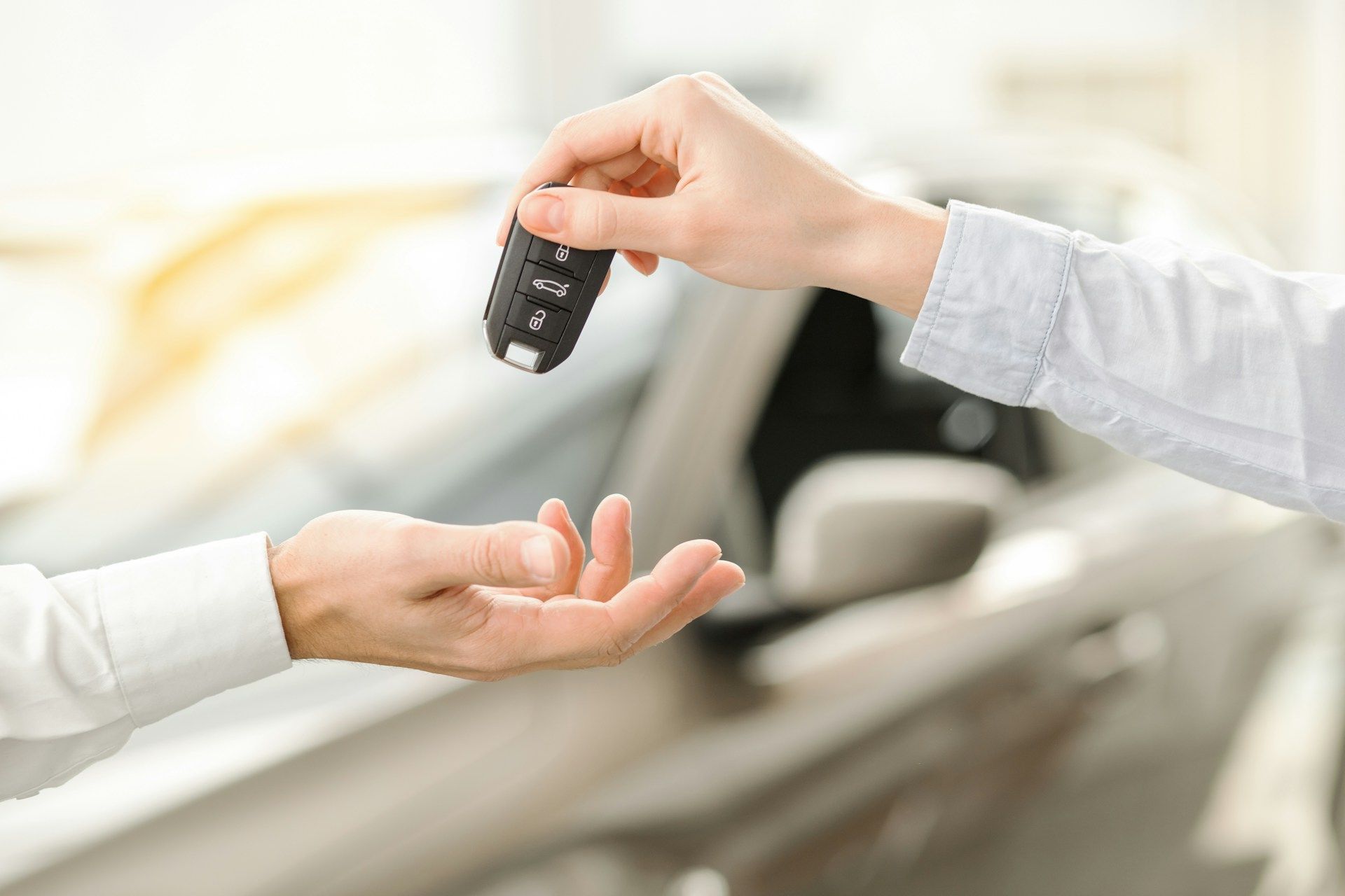 Handing over car keys between two people in a bright showroom