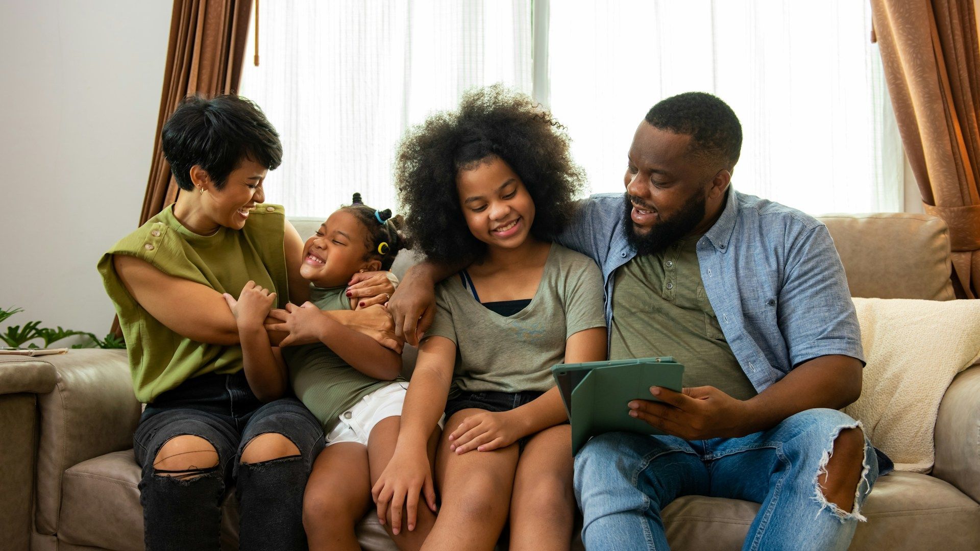 Family sitting on a couch, smiling and reading together in a bright living room