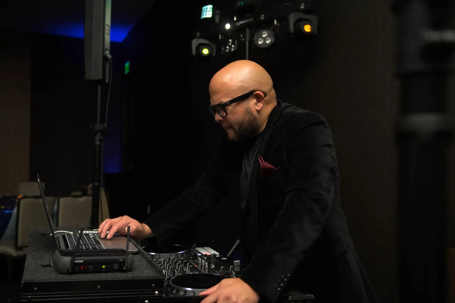 Man in black jacket adjusting audio equipment in a dimly lit studio