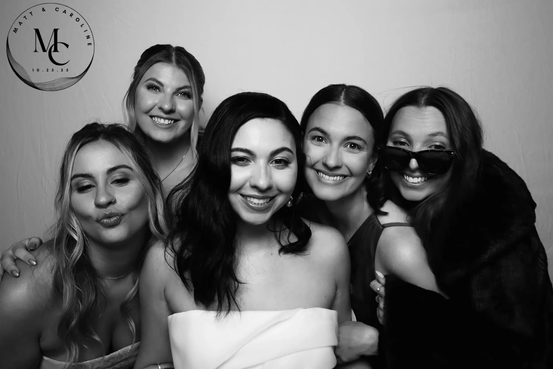 Five people posing closely together, smiling and making playful faces in black-and-white.