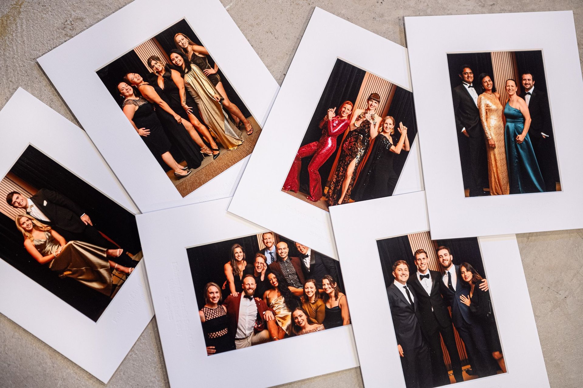 Several framed group photos of people in formal black and red attire spread on a light surface