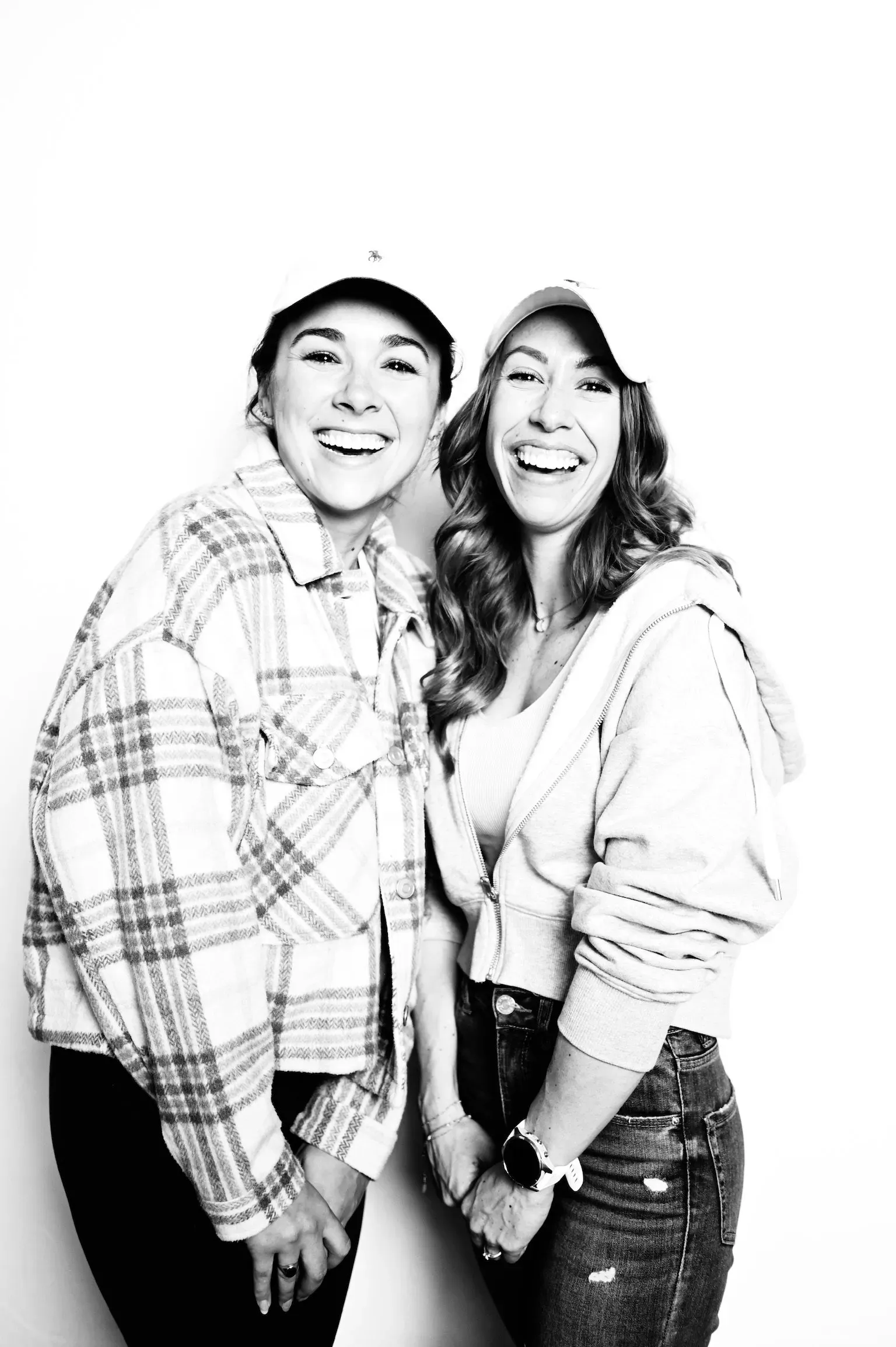 Two people smiling and posing together in casual clothes against a plain white background.