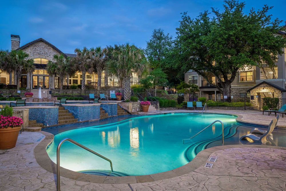 a large swimming pool is lit up at night in front of a building at Marquis Parkside in Austin, TX.