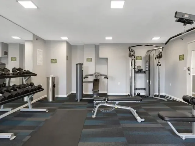 Gym with dumbbells, weight machines, and benches.