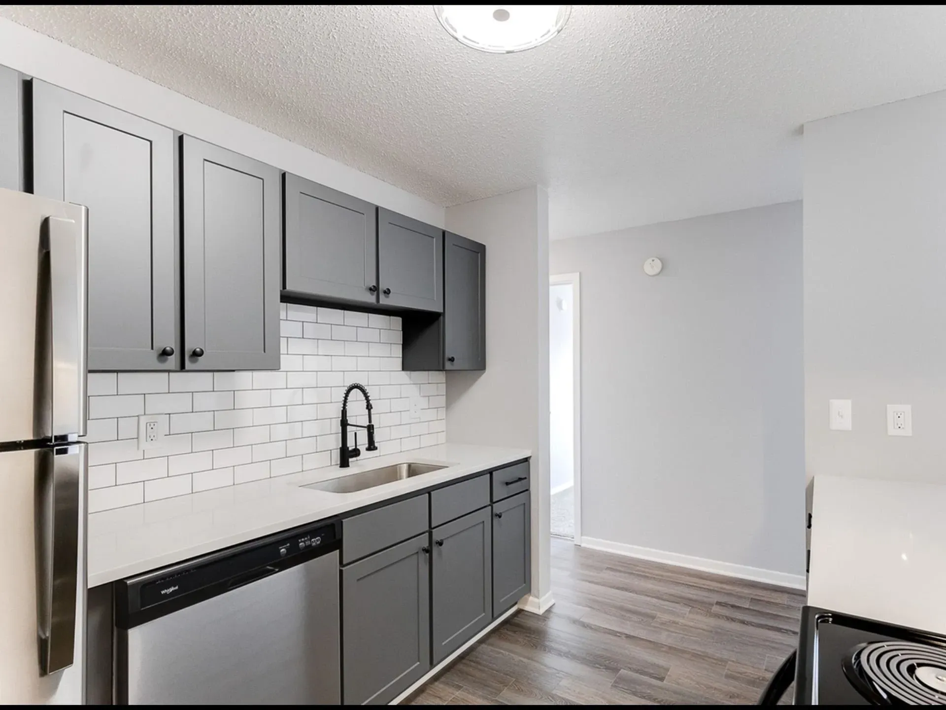 Modern gray kitchen with stainless steel appliances and subway tile backsplash.