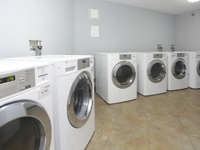 Row of LG washing machines and dryers in a community laundry room.