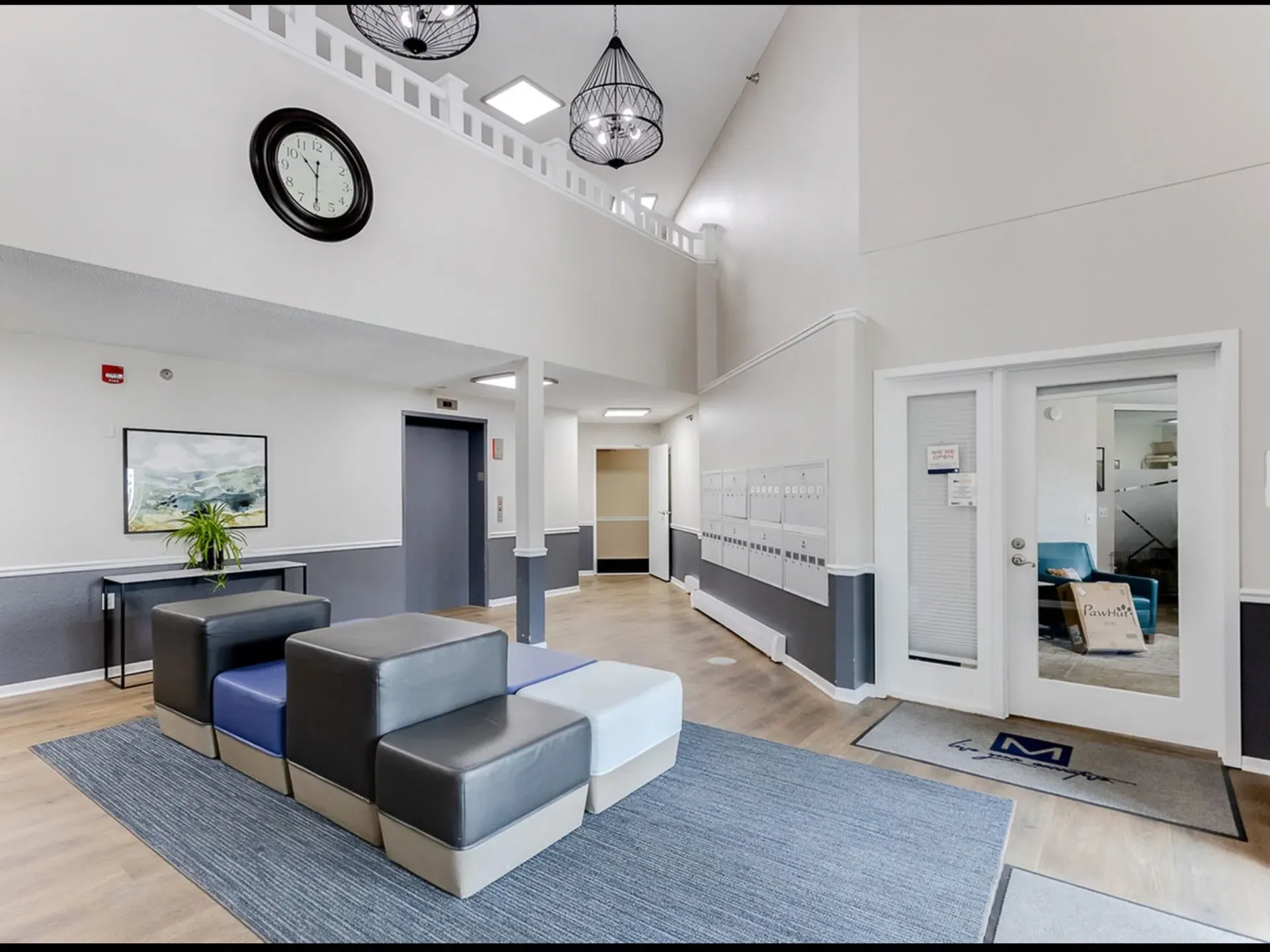 The communal lobby of an apartment building features mailboxes, an elevator, and comfortable seating.