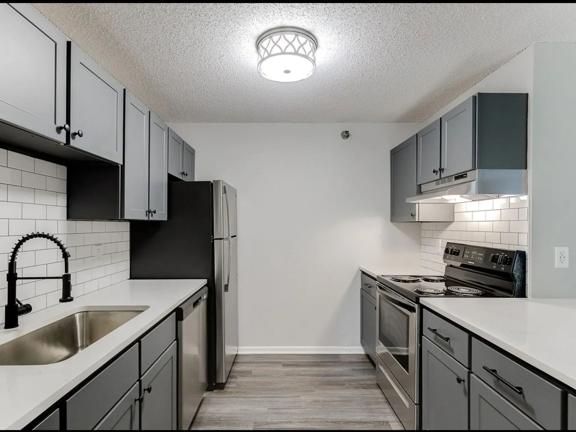 Modern kitchen with gray cabinets, white countertops, and stainless steel appliances.