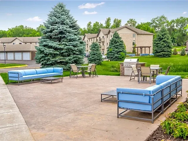 Outdoor patio area with blue sectionals, tables, chairs, and grills.