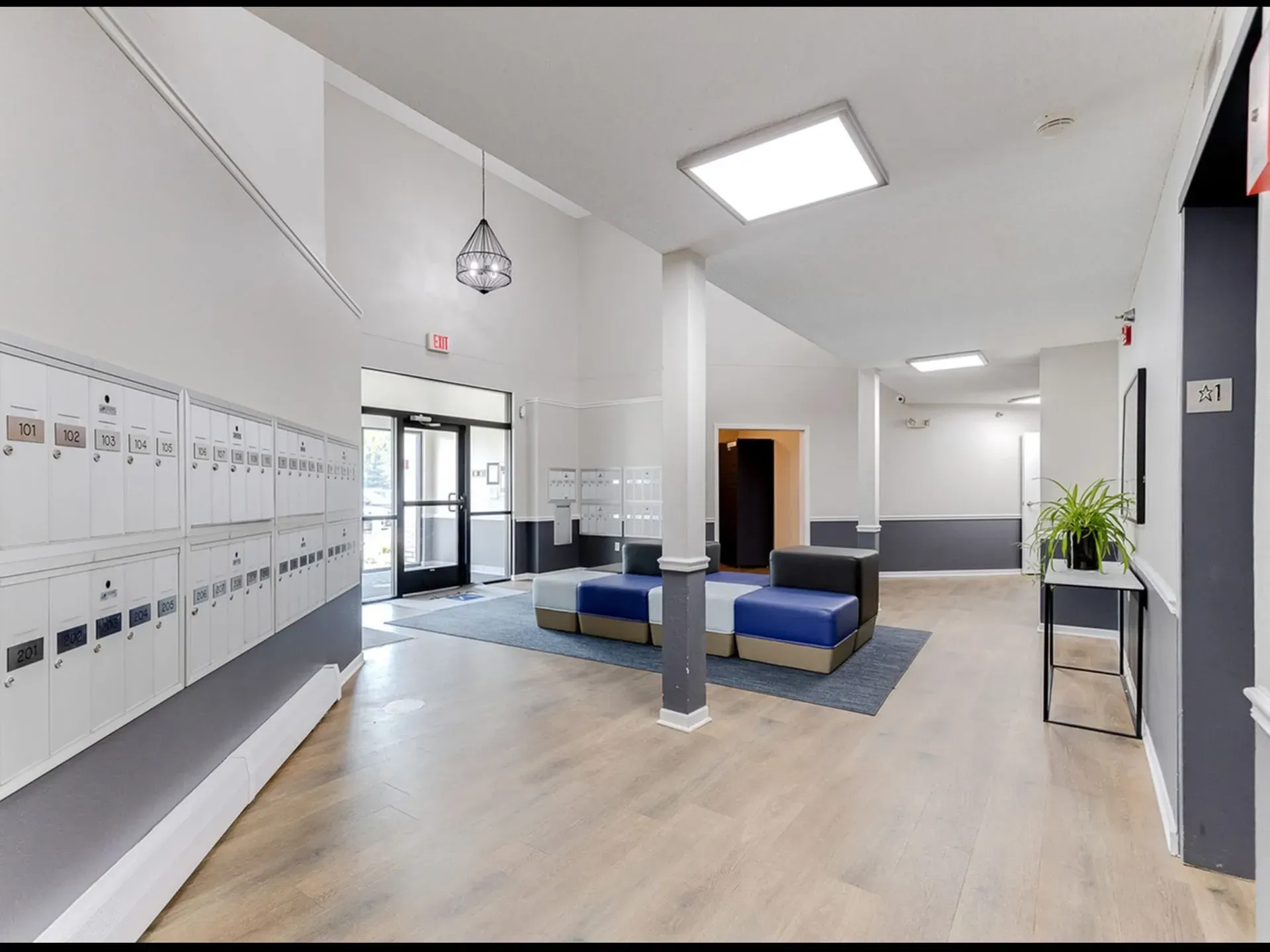 Interior view of apartment building hallway with mailboxes and seating area.