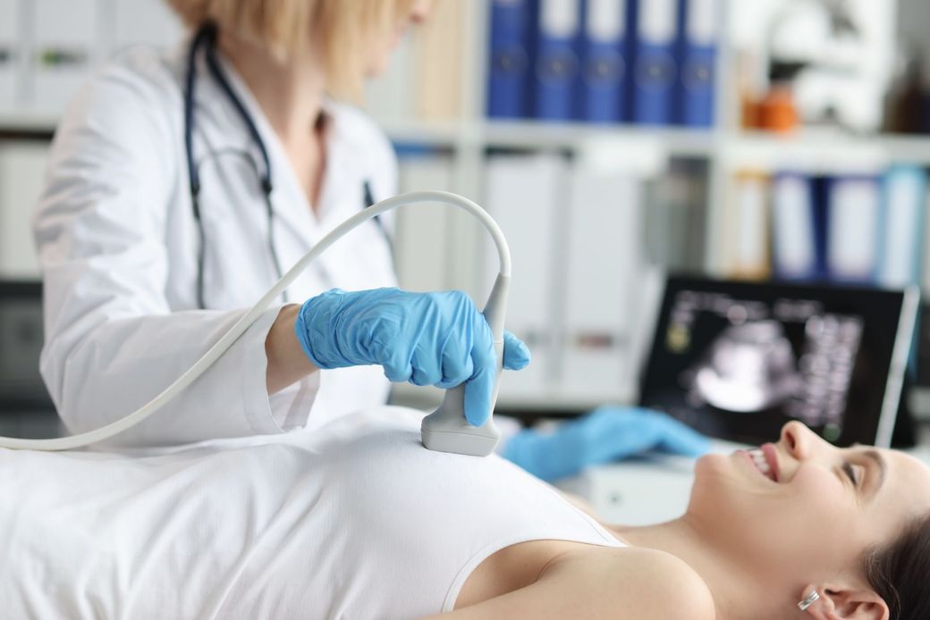 A pregnant woman is getting an ultrasound from a doctor.